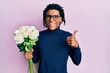© Krakenimages.com - Young african american man holding bouquet of white flowers smiling happy and positive, thumb up doing excellent and approval sign