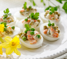 Wall Mural - Close up view of boiled eggs stuffed with mayonnaise and vegetable salad served on a white plate. Delicious easter appetizer