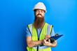 © Krakenimages.com - Redhead man with long beard wearing safety helmet holding clipboard puffing cheeks with funny face. mouth inflated with air, catching air.