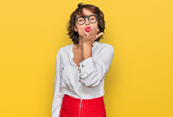 Poster - Young hispanic woman wearing business style and glasses looking at the camera blowing a kiss with hand on air being lovely and sexy. love expression.