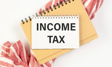 Income Tax Text On Paper On White Table - Business, Banking, Finance And Investment Concept