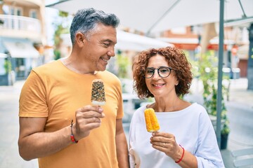 Sticker - Middle age couple smiling happy eating ice cream at street of city.