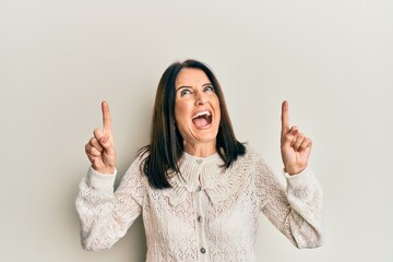 Poster - Middle age brunette woman pointing up with fingers angry and mad screaming frustrated and furious, shouting with anger looking up.