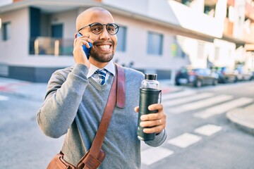 Wall Mural - Young african american businessman smiling happy using smartphone at the city.