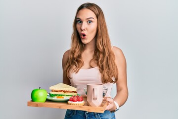 Poster - Young blonde woman holding tray with breakfast food afraid and shocked with surprise and amazed expression, fear and excited face.