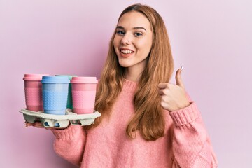 Sticker - Young blonde woman holding tray with take away coffee smiling happy and positive, thumb up doing excellent and approval sign