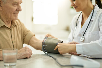 Wall Mural - Professional doctor preparing to check blood pressure of senior man