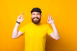 Portrait of young man with beard crossing fingers and wish for something