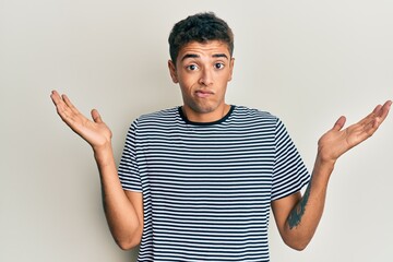 Canvas Print - Young handsome african american man wearing casual clothes clueless and confused with open arms, no idea and doubtful face.