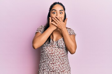 Young latin woman wearing casual clothes shocked covering mouth with hands for mistake. secret concept.