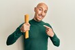 © Krakenimages.com - Bald man with beard holding dry spaghetti smiling happy pointing with hand and finger