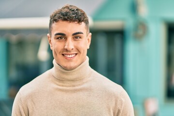 Young hispanic man smiling happy standing at the city.