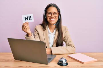 Canvas Print - Beautiful hispanic woman wearing operator headset holding hi paper looking positive and happy standing and smiling with a confident smile showing teeth