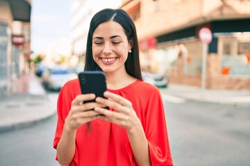 Wall Mural - Young latin girl smiling happy using smartphone at the city.