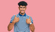 © Krakenimages.com - Young arab man wearing casual clothes and glasses success sign doing positive gesture with hand, thumbs up smiling and happy. cheerful expression and winner gesture.
