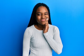 Poster - African american woman with braided hair wearing casual white sweater touching mouth with hand with painful expression because of toothache or dental illness on teeth. dentist