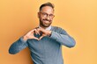 © Krakenimages.com - Handsome middle age man wearing glasses smiling in love doing heart symbol shape with hands. romantic concept.