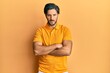 © Krakenimages.com - Young hispanic man wearing casual yellow t shirt skeptic and nervous, disapproving expression on face with crossed arms. negative person.