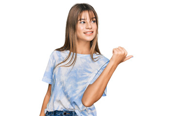 Teenager caucasian girl wearing casual clothes smiling with happy face looking and pointing to the side with thumb up.