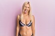 Young blonde woman wearing lingerie sticking tongue out happy with funny expression. emotion concept.