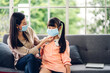 © Art_Photo - Portrait of enjoy happy love asian mother wearing protective mask for little asian girls child in quarantine for coronavirus with social distancing at home.covid19 concept
