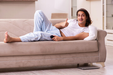 Wall Mural - Young lazy man in oversleeping concept at home