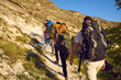 © Studio Romantic - Group of tourists hikers climbing natural rocks with backpacks in row, rear view