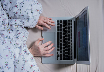 Woman in bed with laptop using internet in online service