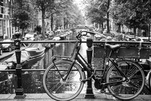 Amsterdam, Holland, May 12 2018: Old Bicycle Parked On A Canal Bridge In Amsterdam