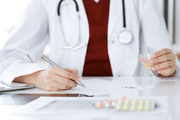 Unknown woman-doctor fills up prescription form. close-up. Panacea and life save, prescribe treatment, legal drug store. Medicine concept