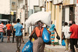 Inhambane, Mozambique, September, 19th 2018: African woman carrying large packages on a street full of men.