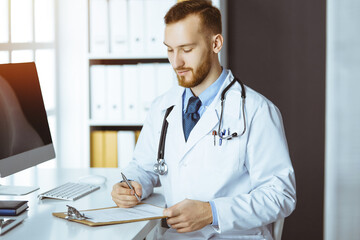 friendly red-bearded doctor and patient woman discussing current health examination while sitting in