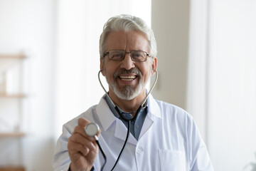 Wall Mural - Headshot portrait of smiling senior Caucasian male doctor in white medical uniform use stethoscope. Profile picture of happy mature man GP or therapist examine patient in hospital. Healthcare concept.