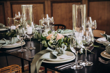 Wedding banquet. The festive table is served with plates with napkins and name cards, glasses and cutlery, and decorated with flower arrangements and candles