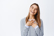 © Cookie Studio - Portrait of smiling good-looking woman with blond hair and white teeth, holding hands on chest in grateful pose, laughing and staring at camera, white background