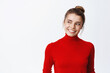 © Cookie Studio - Portrait of stylish young woman with hairbun and natural light make-up, smiling with white teeth, looking left at copy space logo, white background