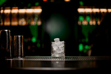 Gorgeous View Of Glass With Ice Standing On Bar Counter On Blurred Background