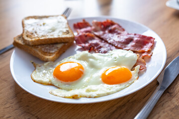 Tasty breakfast with two eggs, bacon, toasts and coffee