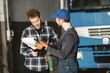 © prostooleh - Two guys talking about work. Work in garage near truck. Transfer of documents with goods