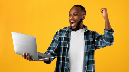 Joyful Black Man Holding Laptop Gesturing Yes Over Yellow Background