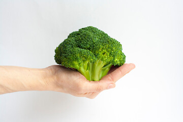 Ripe broccoli in a woman's hand on a white background