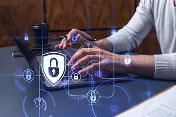 A programmer is typing a code on a keyboard to protect a cyber security from hacker attacks and save clients confidential data. Padlock Hologram icons over the typing hands.