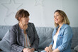 © yavdat - adult daughter talking to his elderly mom. mother and daughter having fun enjoying talk sit on sofa in modern living room. parent relationship concept