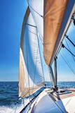 Fototapeta  - Sailing boat at open sea on a bright sunny day, vertical