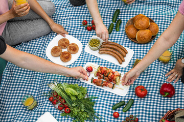 Summer picnic with friends. Delicious food, fresh vegetables, juice, bbq meat, cutlets and sausages.