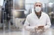 Waist up portrait of adult man working at chemical plant and looking at camera while wearing protective lab coat and mask, copy space