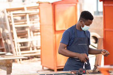 Wall Mural - african carpenter wearing a face mask at work