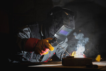 Canvas Print - Welder is welding a metal pipes on the workbench in the dark.