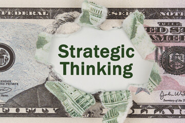 The dollar is torn in the center. In the center it is written - Strategic Thinking