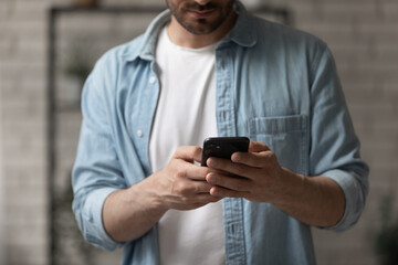 Wall Mural - using phone app. cropped shot of young man in casual clothes hold modern mobile telephone read write